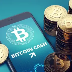 Smartphone zeigt Bitcoin Cash, daneben stapeln sich goldene Bitcoin Cash Münzen.