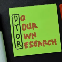 Grüne Notiz mit der Aufschrift "DYOR" (Do Your Own Research) und zwei Markern. Die DYOR Bedeutung ist klar: Eigeninitiative bei der Recherche.