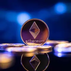 Eine glänzende Ethereum-Münze, die das Symbol und den Namen trägt, steht im Fokus. Sie ist Teil einer Ansammlung von Münzen, die auf einer dunklen, spiegelnden Oberfläche liegen und die Zukunft von eth 2.0 symbolisieren.