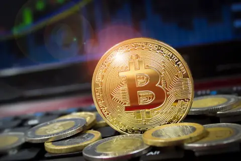 Goldener Bitcoin-Coin auf Tastatur, umgeben von Münzen. Ein Blick zurück auf den Bitcoin Preis 2009, als die Kryptowährung noch in den Kinderschuhen steckte.