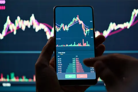 Hand hält Smartphone mit Bitcoin-Chart und Orderbuch. Der Kurs fällt, was auf einen möglichen Bitcoin short hindeutet.