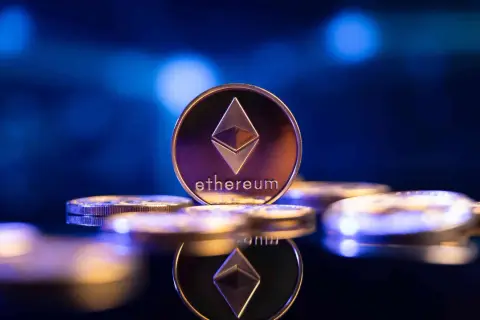 Eine glänzende Ethereum-Münze, die das Symbol und den Namen trägt, steht im Fokus. Sie ist Teil einer Ansammlung von Münzen, die auf einer dunklen, spiegelnden Oberfläche liegen und die Zukunft von eth 2.0 symbolisieren.