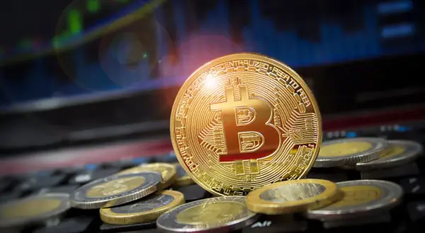 Goldener Bitcoin-Coin auf Tastatur, umgeben von Münzen. Ein Blick zurück auf den Bitcoin Preis 2009, als die Kryptowährung noch in den Kinderschuhen steckte.