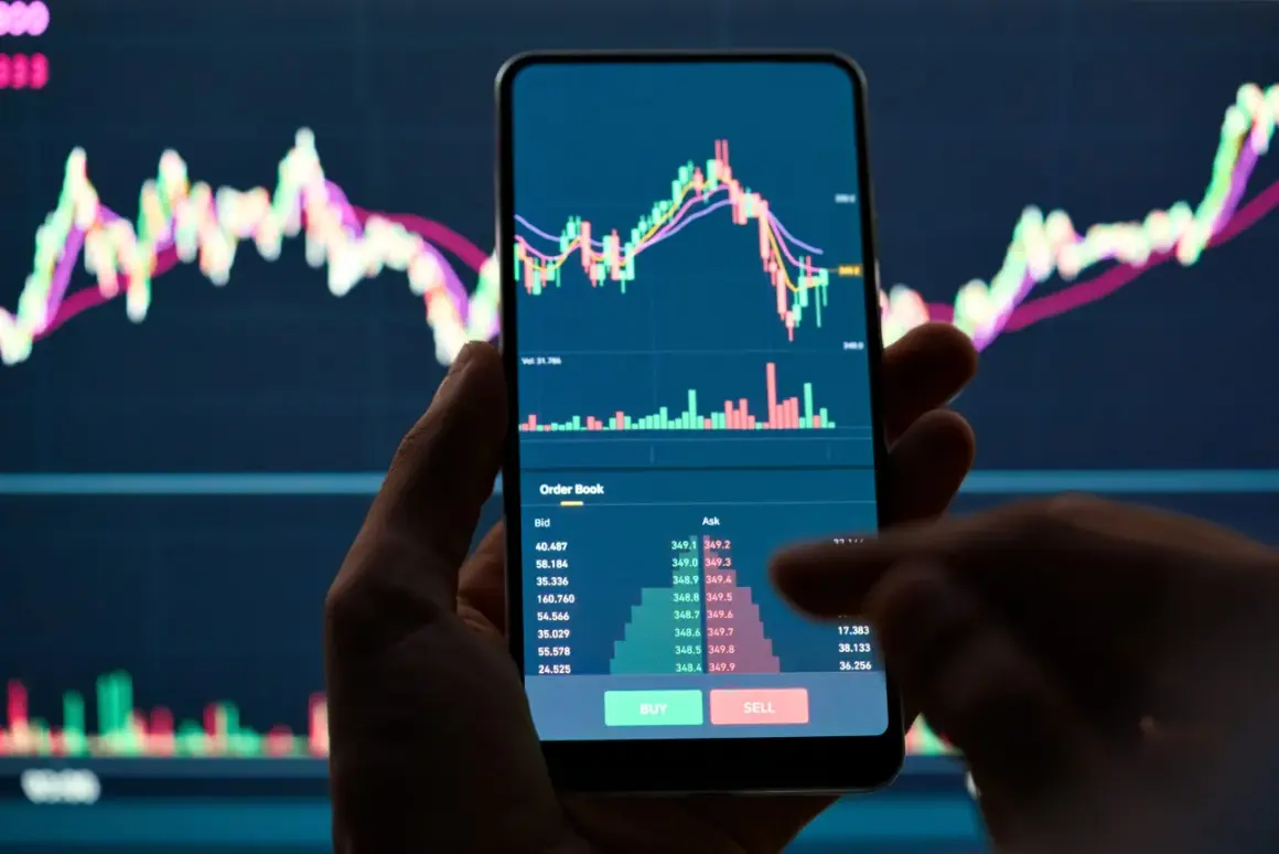 Hand hält Smartphone mit Bitcoin-Chart und Orderbuch. Der Kurs fällt, was auf einen möglichen Bitcoin short hindeutet.