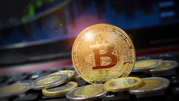 Goldener Bitcoin-Coin auf Tastatur, umgeben von Münzen. Ein Blick zurück auf den Bitcoin Preis 2009, als die Kryptowährung noch in den Kinderschuhen steckte.